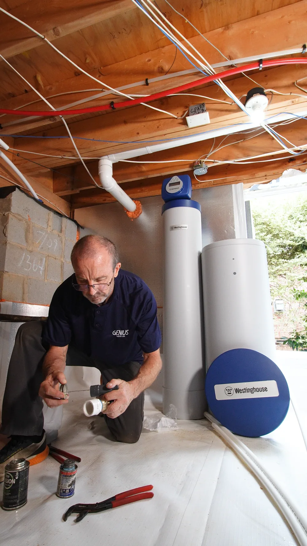 Genius Water Co. technician installing a whole-home filtration system in a garage